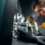 Mécanicien en vêtements de protection debout dans le montage de pneus près de la voiture et vérifiant l'étrier