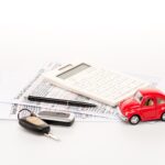 Clés, calculatrice, certificats d'assurance et voiture de jouets rouges sur la surface blanche