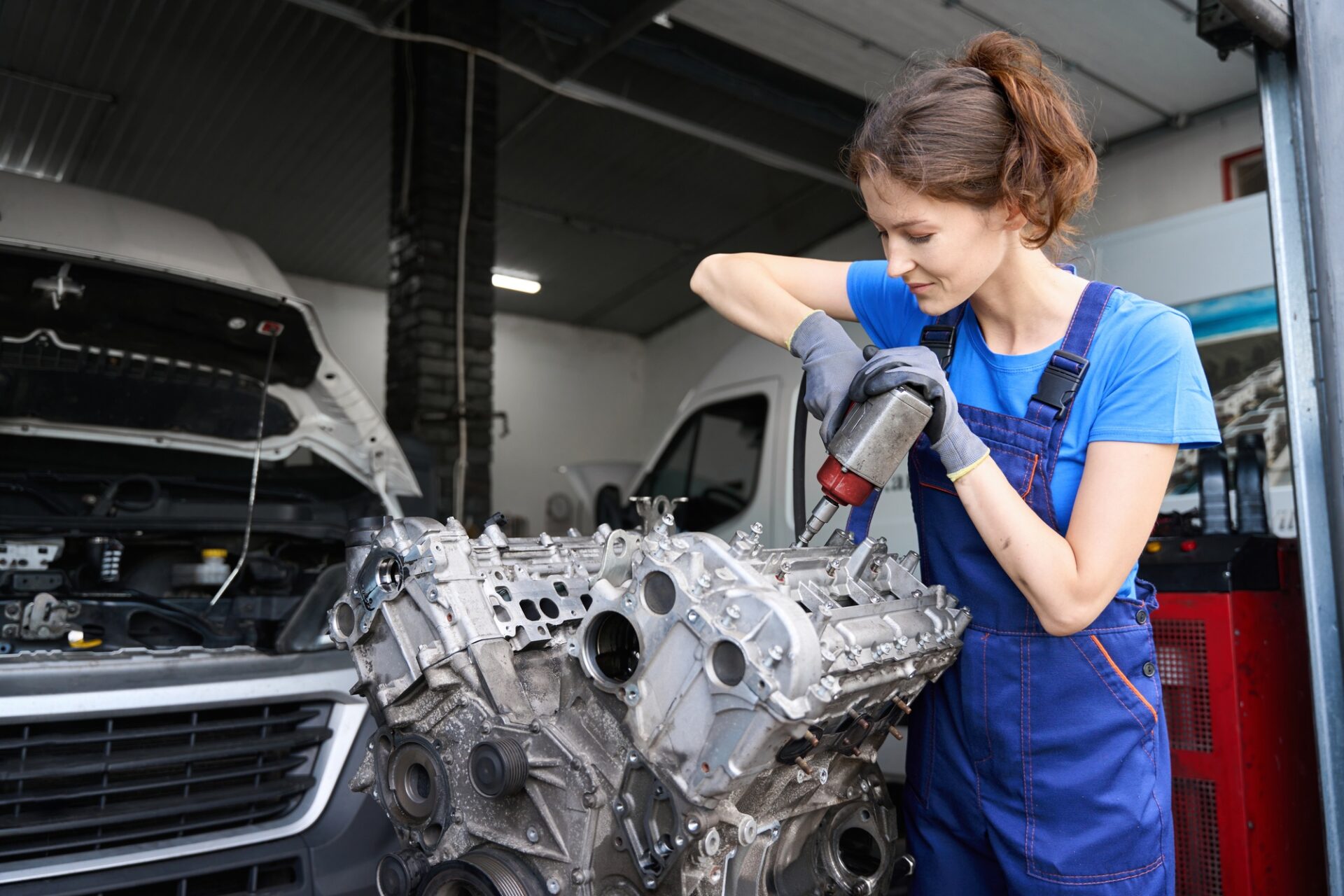 Young Woman Master répare un moteur de voiture, elle utilise un outil spécial