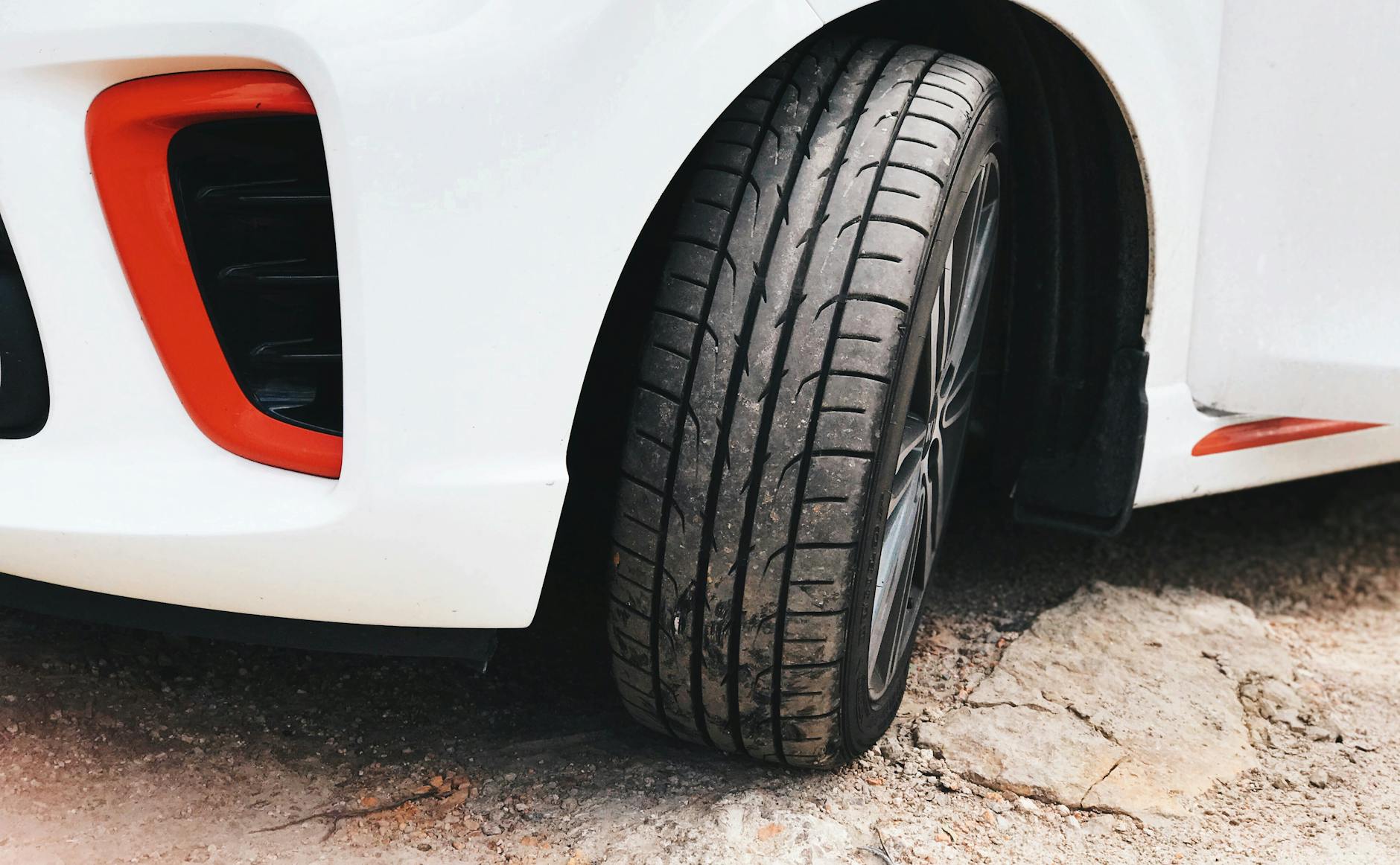 Vue détaillée d'un pneu de voiture blanche sur une surface rocheuse, mettant en évidence sa bande de roulement et sa conception.
