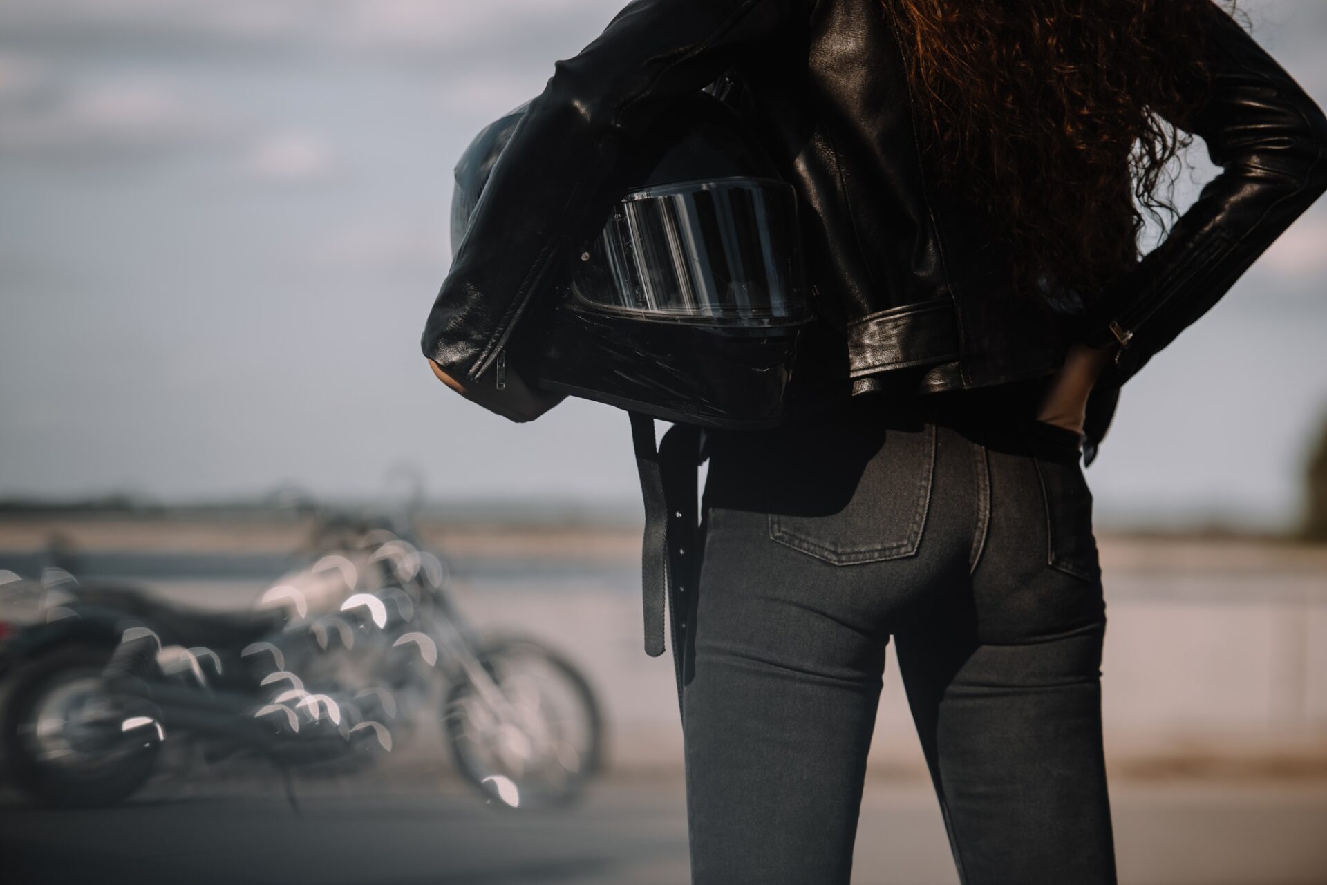 Vue courte de la femme tenant un casque de moto, moto debout sur fond