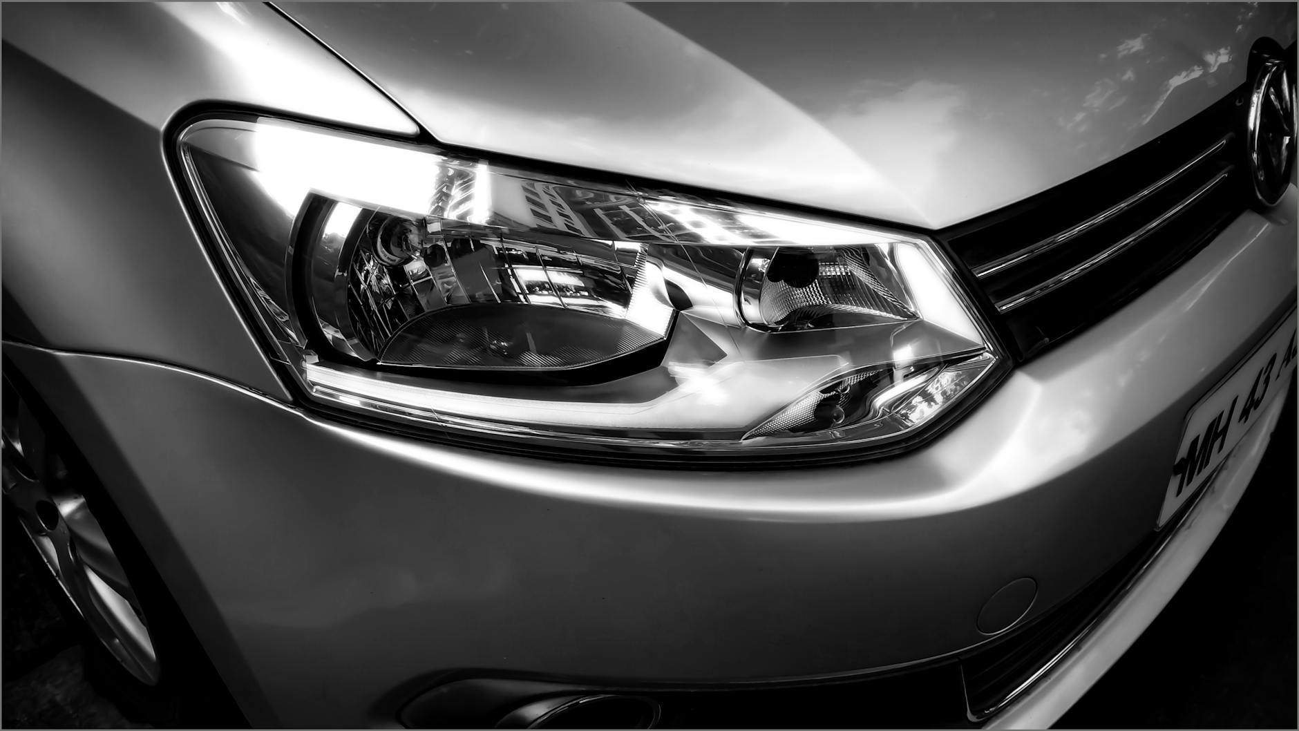 Image détaillée d'un phare de voiture Volkswagen en monochrome.