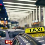 Éclairage du taxi panneau sur le toit de la voiture contre le terminal de l'aéroport la nuit.
