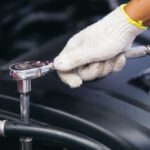 Mécanicien de gros plan des employés à la main Usure du gant Réparation de travail de la réparation de voiture cassée dans un atelier de réparation automobile.